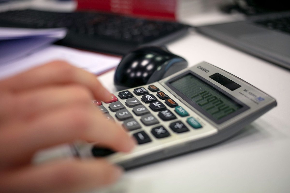 Main tapant sur une calculatrice avec un écran numérique Main tapant sur une calculatrice avec un écran numérique