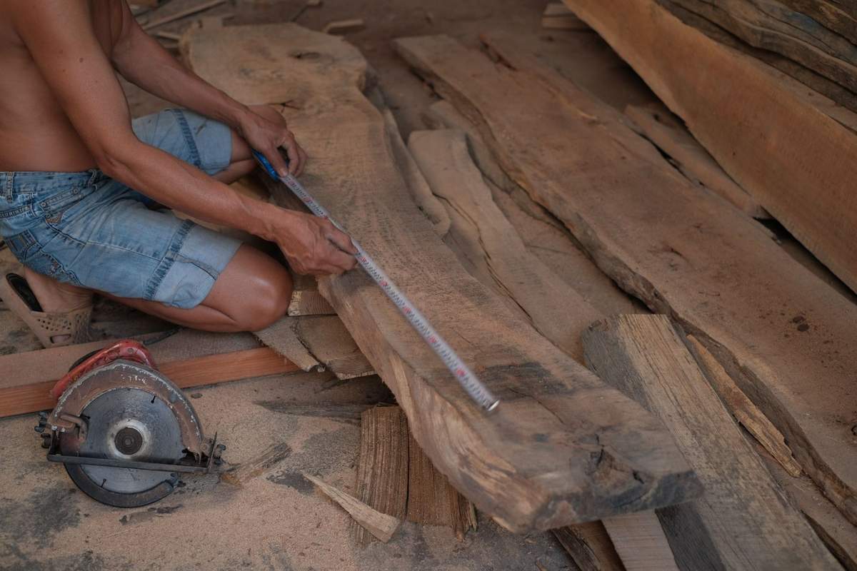 Homme utilisant une scie pour couper du bois dans un atelier en plein air Homme utilisant une scie pour couper du bois dans un atelier en plein air