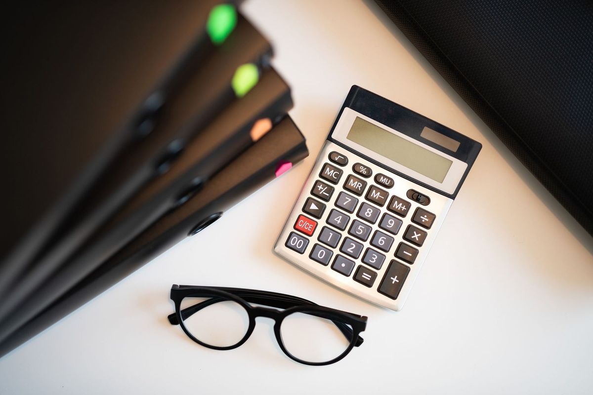 Calculatrice, lunettes, classeurs colorés sur un bureau