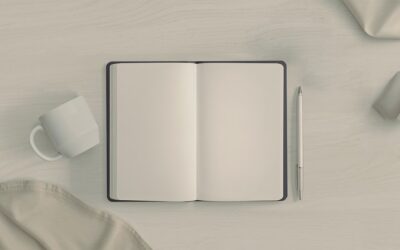 Carnet ouvert avec pages blanches, stylo et tasse blanche sur bureau épuré