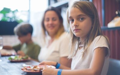 Jeune fille assise à table avec une assiette devant elle