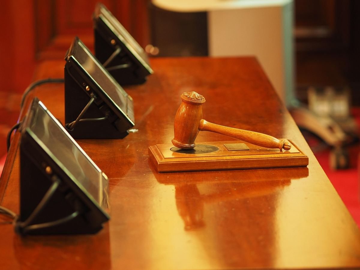 Marteau de juge en bois sur un bureau avec microphones, dans une salle d'audience Marteau de juge en bois sur un bureau avec microphones, dans une salle d'audience
