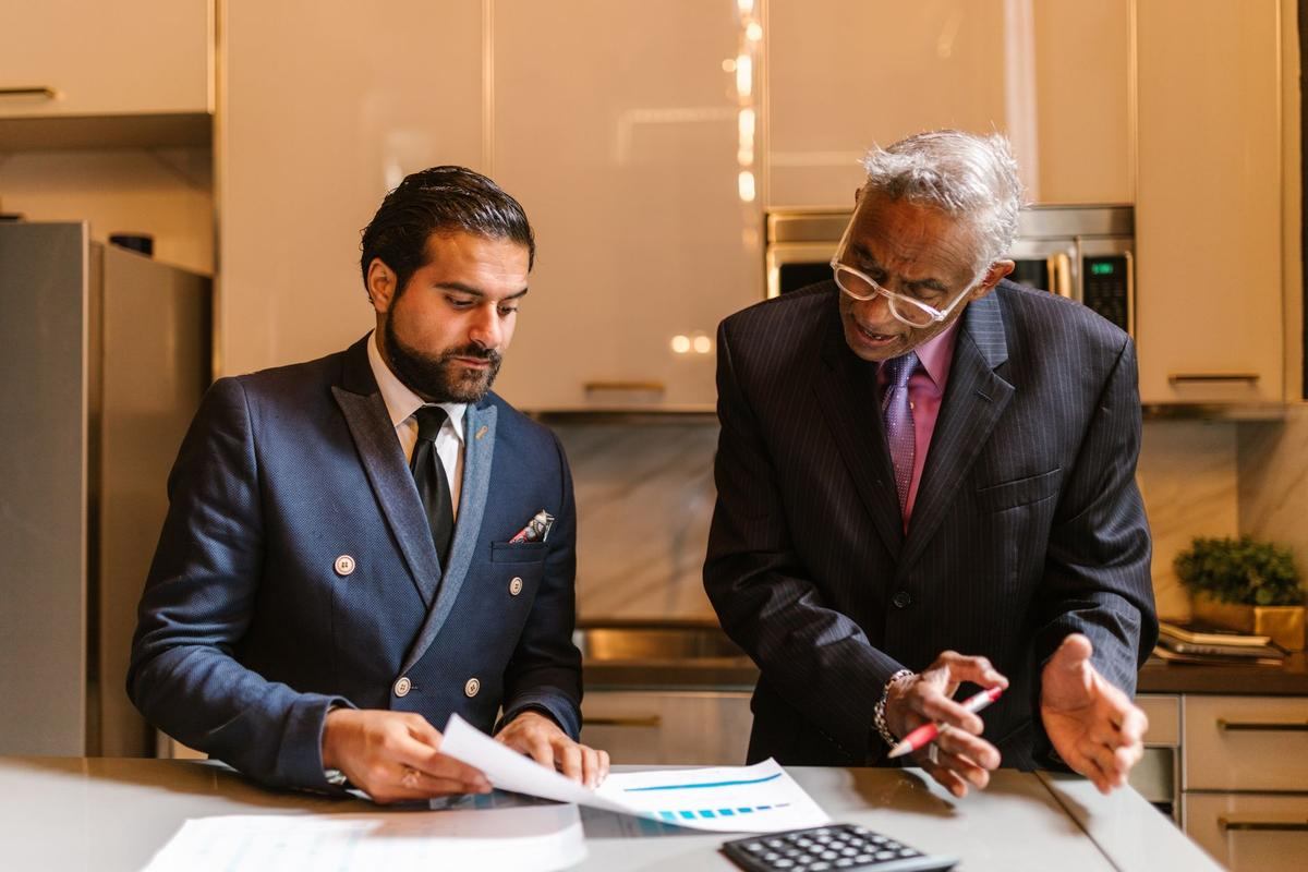 Deux dirigeants en costume examinent des documents à un bureau dans un bureau moderne Deux dirigeants en costume examinent des documents à un bureau dans un bureau moderne