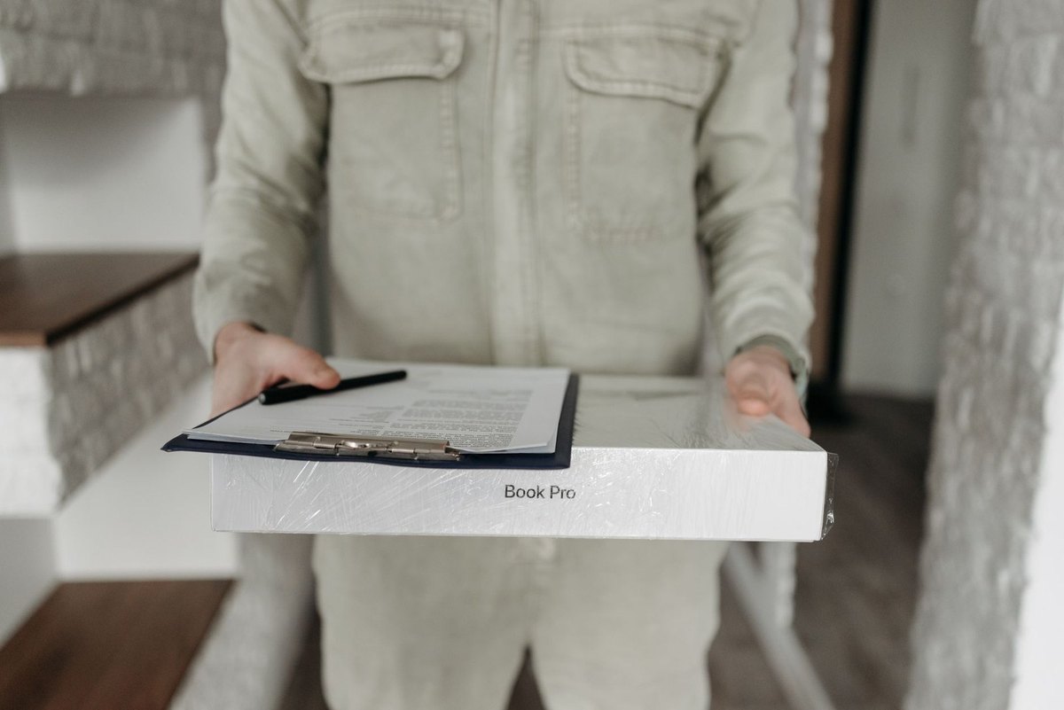 Personne en blouse blanche portant un classeur avec carnet et stylo à l'intérieur d'un bâtiment Personne en blouse blanche portant un classeur avec carnet et stylo à l'intérieur d'un bâtiment