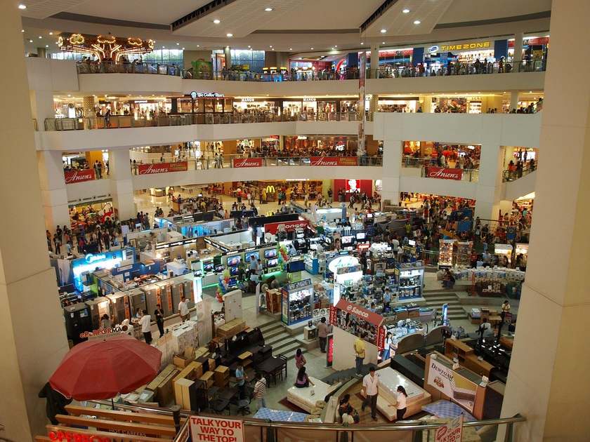 Intérieur d'un grand centre commercial avec plusieurs étages de magasins et d'escaliers