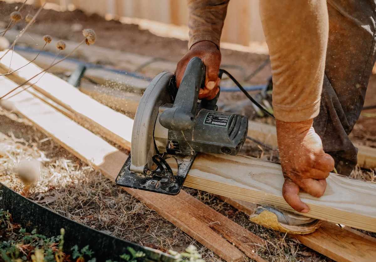 Homme coupant du bois avec une scie circulaire sur une terrasse Homme coupant du bois avec une scie circulaire sur une terrasse