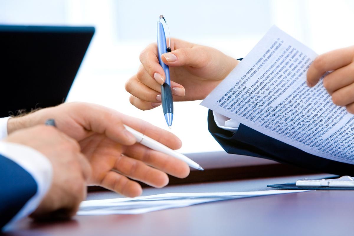 Deux personnes signent un papier avec stylos sur une table Deux personnes signent un papier avec stylos sur une table