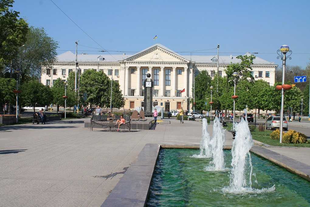 Bâtiment avec colonnes et fontaine devant, avenue bordée d'arbres Bâtiment avec colonnes et fontaine devant, avenue bordée d'arbres