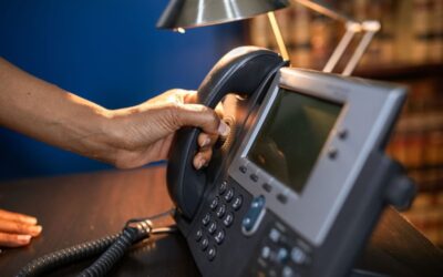 Une main saisit le combiné d'un téléphone de bureau